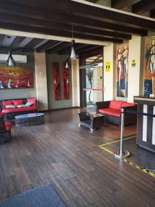 uma sala de estar com mobiliário vermelho e pinturas nas paredes em Lindo DPTO en Condominio Cama KING em Santa Cruz de la Sierra