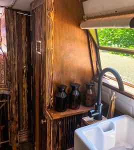 BishopbriggsにあるSNUG 30ft NARROWBOAT WITH FIREPLACEのキッチン(シンク、黒い花瓶4本付)