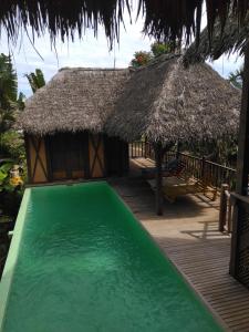 un complexe avec une piscine et un toit de chaume dans l'établissement LOCAVACATION Les Hauts Manguiers Villa 2, à Nosy Be