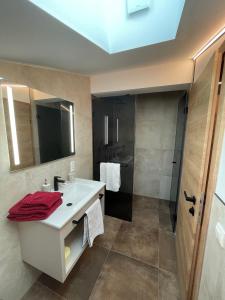 La salle de bains est pourvue d'un lavabo blanc et d'une douche. dans l'établissement Obermühlhof, à Saalfelden