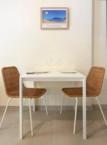 une table blanche avec deux chaises et une photo sur le mur dans l'établissement Studio Le Provençal proche plage, à Saint-Mandrier-sur-Mer