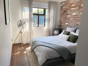 a bedroom with a bed and a brick wall at Chic Loft Style Apartment in Perth