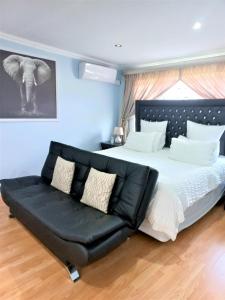 a bedroom with a large bed with a black leather couch at JB Countrylife Accommodation in Centurion