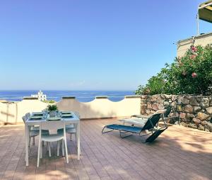 una mesa y sillas en un patio con vistas al océano en Casa Rais Dragut en Capraia