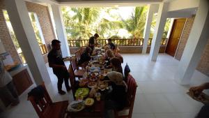 a group of people sitting at a long table in a restaurant at MIN Guest House Watukarung in Pacitan