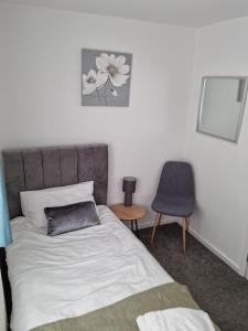 um quarto com uma cama, uma cadeira e uma mesa em Entire House - Cheshire Oaks/Ellesmere Port em Ellesmere Port