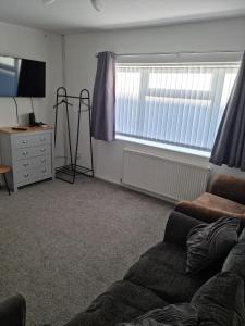 a living room with a couch and a window at Entire House - Cheshire Oaks/Ellesmere Port in Ellesmere Port