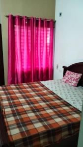 耶勒幾里的住宿－Tulips Misty hights 2BHK villa，一间卧室配有一张带粉红色窗帘的床