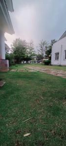 a grassy yard with a white building and trees at Tulips Misty hights 2BHK villa in Yelagiri