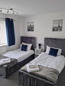 a bedroom with two beds and a ottoman sidx sidx sidx sidx at Entire House - Cheshire Oaks/Ellesmere Port in Ellesmere Port