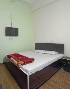 een slaapkamer met een bed met witte lakens en een televisie bij OYO Hotel Mongoose Palace in Narela