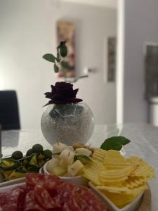 Montefalcone di Val FortoreにあるLa Perla Del Borgoのチップスとクラッカーの皿とバラの花瓶