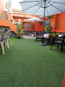 een patio met groen gras en een parasol bij Villa Cantora in Telde