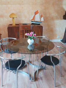 a glass table with two chairs and a vase with flowers at le cottage vue mer in Bénerville-sur-Mer