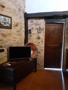 Cette chambre dispose d'une porte, d'un canapé et d'une télévision. dans l'établissement Casa do Terreto & Casa do Forno, à Parada