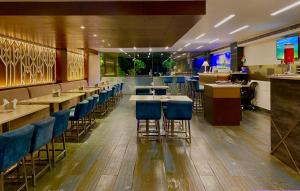 a restaurant with blue chairs and tables and a bar at Ace Iconic in Greater Noida