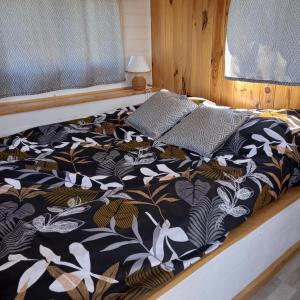 a bed with a black and white comforter and a window at Camping car vintage in Saint-Barthélemy-le-Plain