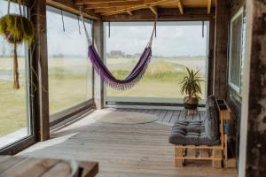 a porch with a hammock and a room with a window at Tiny Farm House met hot tub. in Menaldum
