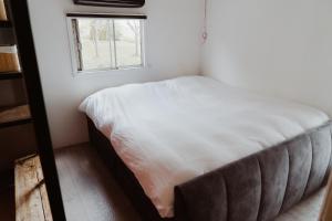 a bed in a small room with a window at Tiny Farm House met hot tub. in Menaldum