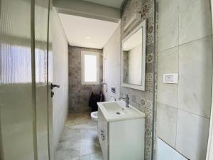 een badkamer met een wastafel, een toilet en een spiegel bij Villa Fadhloun 1 in Awlād ‘Umar