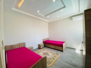 een kamer met 2 bedden met rode lakens en een tapijt bij Villa Fadhloun 1 in Awlād ‘Umar