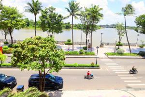 una calle con coches y gente en motocicleta y un lago en Bcons Riverside Hotel Binh Duong en Thu Dau Mot