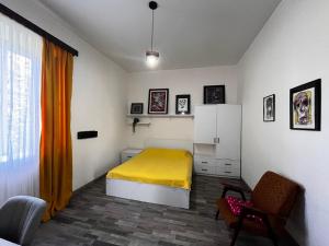 sypialnia z żółtym łóżkiem i krzesłem w obiekcie Mziuri Guest House w mieście Gonio