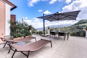 eine Terrasse mit einem Tisch, Stühlen und einem Sonnenschirm in der Unterkunft Suite La Panoramica in Massa Lubrense