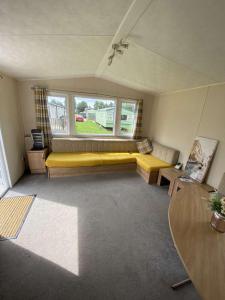 a living room with a yellow couch and a window at Impeccable 3 bedroom lodge pet friendly in Northampton