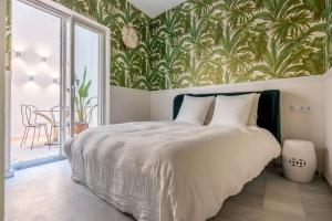 1 dormitorio con 1 cama con papel pintado tropical en Designer Apartment en Sevilla