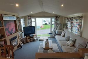 a living room with a couch and a tv at Arual Caravan Manor House Park. Allonby, Cumbria in Maryport
