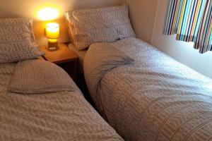 two beds in a bedroom with a lamp on a table at Arual Caravan Manor House Park. Allonby, Cumbria in Maryport