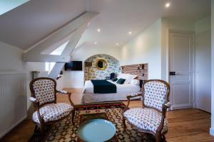 a bedroom with a bed and two chairs at Le Relais du Faget 