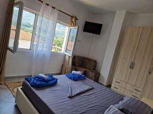 Schlafzimmer mit einem Bett mit blauer Bettwäsche und einem Fenster in der Unterkunft Bar-Restaurant-Hotel-Familja in Klos