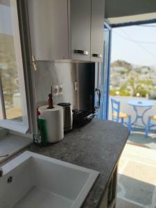 a kitchen counter top with a sink and a window at Neo-Traditional Sunrise Apartment in Ios Chora