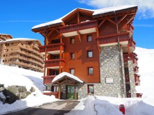 um grande edifício de madeira com neve no chão em Appartement Les Menuires, 3 pièces, 6 personnes - FR-1-178-373 em Les Menuires