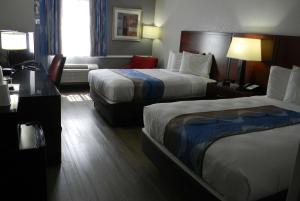 a hotel room with two beds and a desk at Travelodge Inn & Suites by Wyndham Albany in Albany