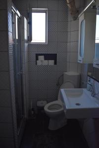 a bathroom with a toilet and a sink and a window at MANEVI Apartment in Strumica