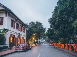 a red car parked on the side of a street at 3 Nagas Luang Prabang - MGallery Hotel Collection in Luang Prabang