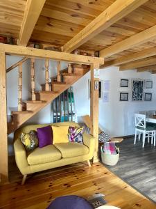 a living room with a yellow couch and wooden stairs at Vila Gorska in Žabljak