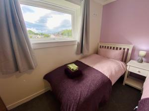 a small bedroom with a bed and a window at cosy town bungalow in Inverlochy