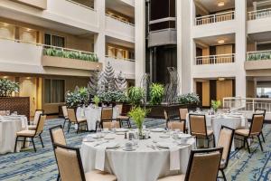 un salón de banquetes con mesas y sillas blancas en Embassy Suites by Hilton Boston Waltham, en Waltham
