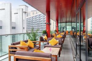 uma fila de cadeiras com almofadas amarelas numa varanda em Hilton London Wembley em Londres