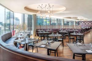 a restaurant with tables and chairs and windows at Hilton London Wembley in London