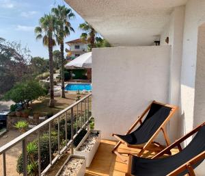 un balcón con 2 sillas y una piscina en Apartamento muy tranquilo con piscina, en Tossa de Mar