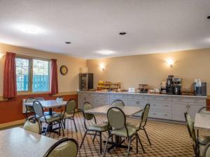 a room with tables and chairs and a kitchen at Travelodge by Wyndham Lacombe in Lacombe