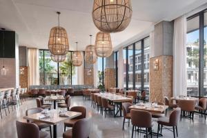 um restaurante com mesas e cadeiras e janelas grandes em Hyatt Centric Downtown Nashville em Nashville