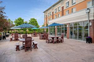 un patio al aire libre con mesas, sillas y sombrillas en Wyndham Noblesville, en Noblesville