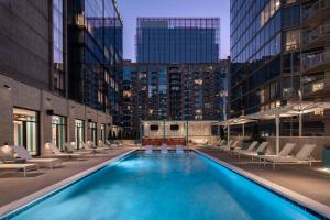 una piscina en una ciudad con sillas y edificios en Hyatt Centric Downtown Nashville en Nashville