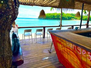 a wooden deck with chairs and a bar on the water at Sand and Tan Beach Hotel in Ocho Rios
